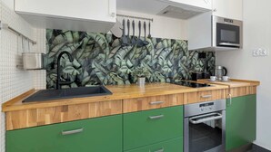 A kitchen with a wooden countertop, green cabinets, a microwave, and a stove.