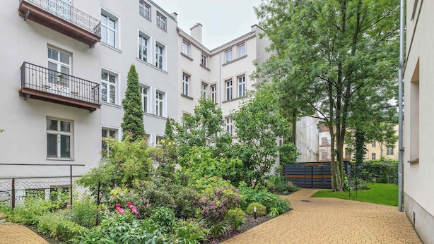 Un patio con un sendero empedrado, rodeado de edificios de varios pisos con balcones y ventanas.