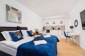 Une chambre d’hôtel moderne équipée d’un grand lit, d’un bureau et d’une kitchenette.