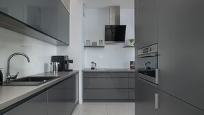 A modern kitchen with sleek cabinetry, a stainless steel sink, a coffee machine, and a microwave.