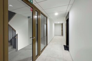 A corridor with a glass door, a staircase, and a sign indicating an exit. - Stylish Apartment in Wroclaw | Balcony | Parking (Wrocław)