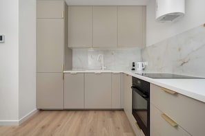 Een moderne keuken met een wit aanrecht, een ingebouwde oven en een roestvrijstalen afzuigkap.