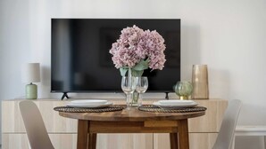 Une table à manger ornée d’un vase de fleurs, de deux verres à vin et de deux assiettes.