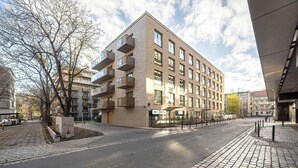 Un immeuble à plusieurs étages doté de balcons, une rue pavée et un trottoir.