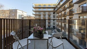 Un balcon avec une table, des chaises et un arrangement floral.