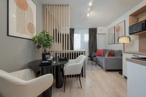 A modern living space with a dining area, a sofa, and a kitchen.