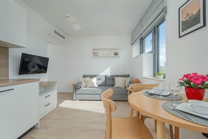 A modern living space with a kitchen, dining area, and a grey sofa.