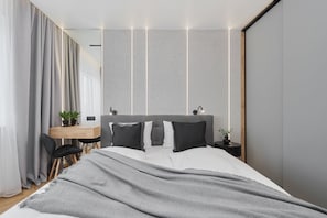 A modern bedroom with a bed, bedside tables, a desk, and a chair.