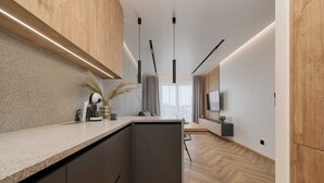 Una cocina moderna con una isla integrada, iluminación colgante y vista al área de estar.