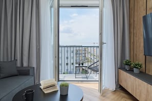 A modern living room with a sofa, a coffee table, a bookshelf, and a balcony with a railing.
