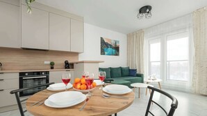 Comedor con una mesa de madera dispuesta para cuatro, un frutero y copas de vino.