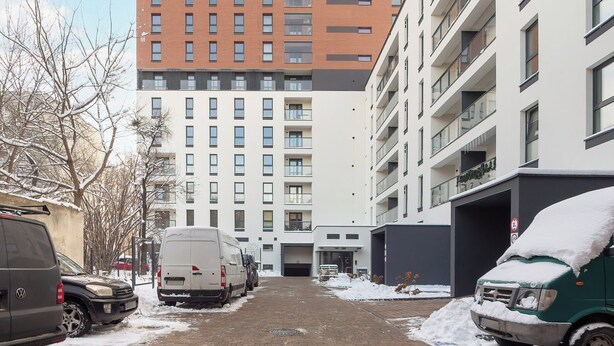 A multi-story parking garage with vehicles parked inside, surrounded by buildings. - Modern Apartment | Parking | Close to Atlas Arena (Łódź)