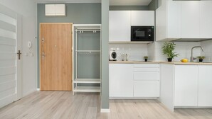 Una cocina moderna con armarios blancos, un microondas y una puerta de madera.