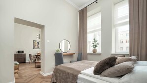 Ein Schlafzimmer mit einem Bett, einem Schreibtisch, einem Stuhl, einem Spiegel und einem Fenster mit Vorhängen.