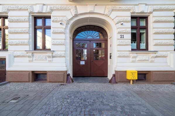 A building entrance with a double door, a number plaque, and a yellow sign.