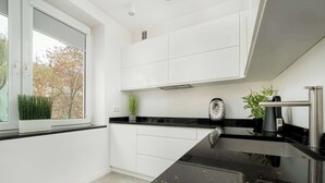 A modern kitchen with white cabinets, a black countertop, and a window with a view of trees.
