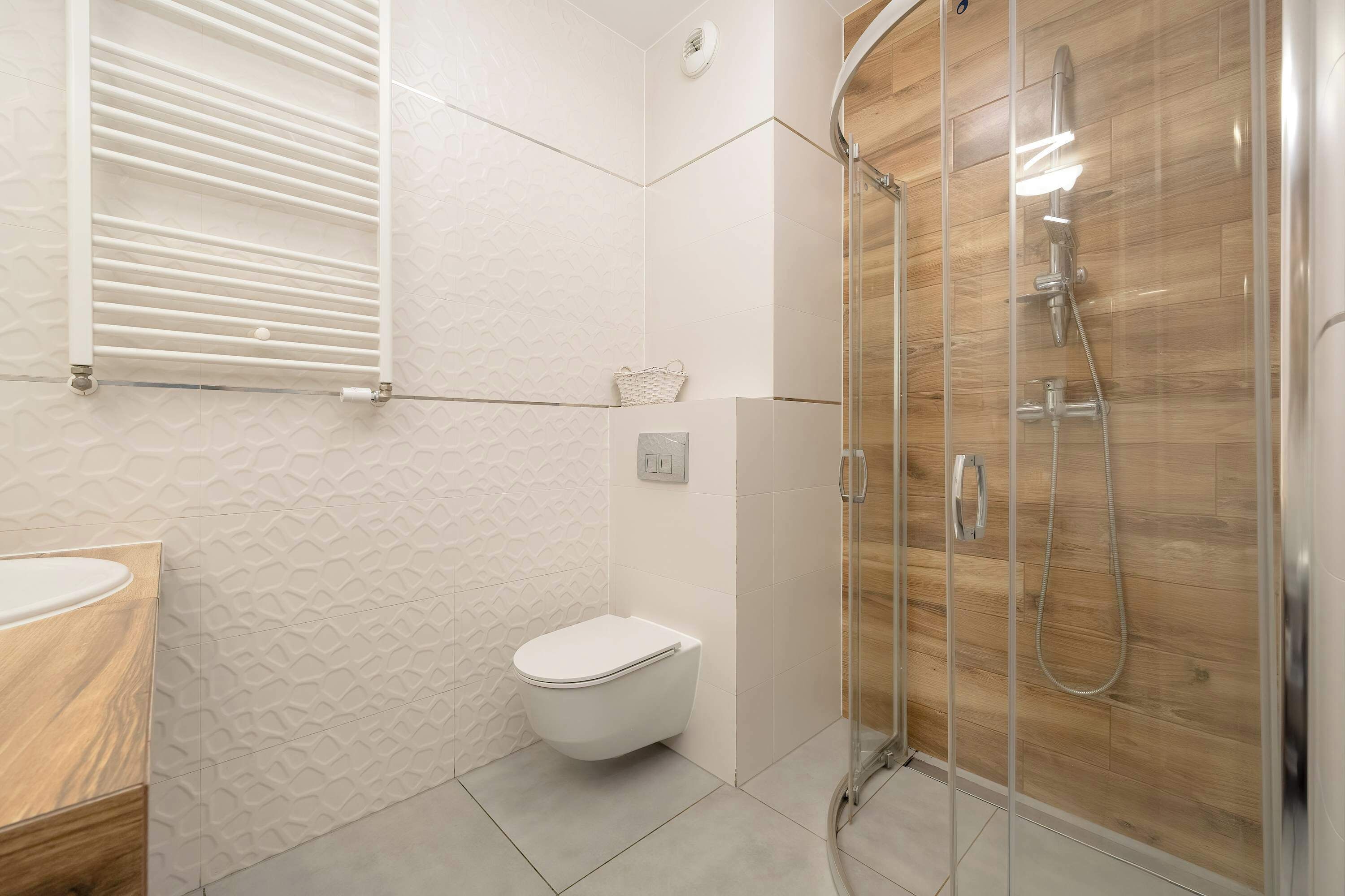 Un baño moderno con inodoro, ducha y tocador de madera.