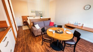 A compact living space with a sofa, a dining table, and a kitchenette. - Zum Brandenburger Tor 01 (Damme)