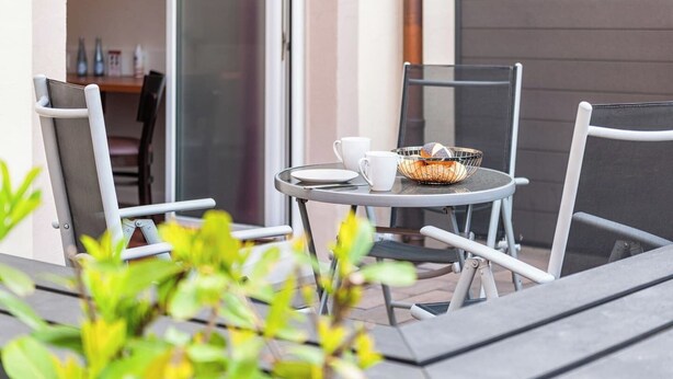 A small outdoor seating area with a round table, two chairs, and a bowl of bread. - Zum Brandenburger Tor 01 (Damme)
