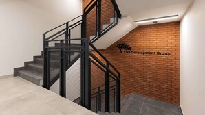 Eine Treppe mit schwarzen Metallgeländern und einer Ziegelwand mit einem Logo.