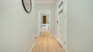 Un pasillo con piso de madera que conduce a un dormitorio con cama y ventana.