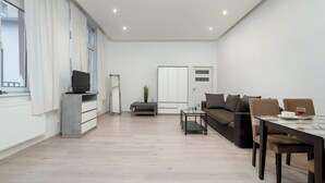 Un salón amplio con sofá, una mesa de comedor y un televisor sobre un mueble.