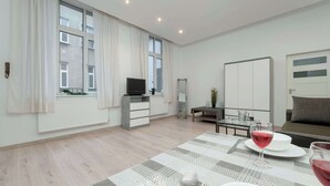 Una sala de estar moderna con comedor, ventanas amplias, televisor de pantalla plana y sofá.