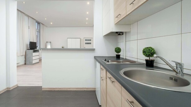Una cocina moderna con un lavamanos grande, armarios de madera y una encimera.