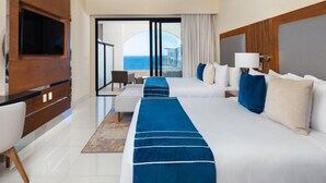 Une chambre d’hôtel avec deux lits, une télévision, un ventilateur de plafond et une vue sur la mer.