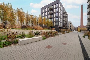 A modern building with balconies, a brick chimney, and a landscaped walkway. - Bright Studio with Balcony | Ideal for Remote Work (Łódź)
