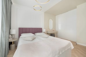 Une chambre moderne avec un grand lit, des tables de chevet, un miroir et une porte.