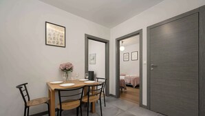 A dining area with a wooden table and chairs, a vase with flowers, and framed pictures on the wall. - Stylish Apartment with Balcony | Parking Space (Wrocław)