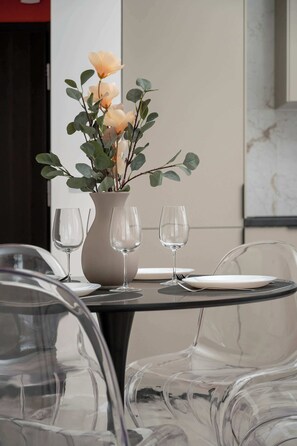 A dining table with a vase of flowers, two wine glasses, and a plate.