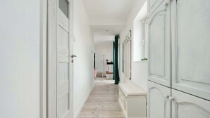 A narrow hallway with white doors and a bench. - Spacious Apartment in the City Center | Balcony | 2 Bedrooms (Łódź)