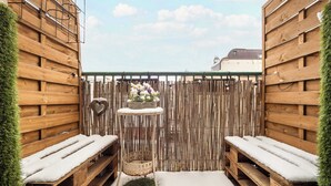 A wooden outdoor seating area with benches and a small table, surrounded by a bamboo fence and a wooden wall. - Spacious Apartment in the City Center | Balcony | 2 Bedrooms (Łódź)