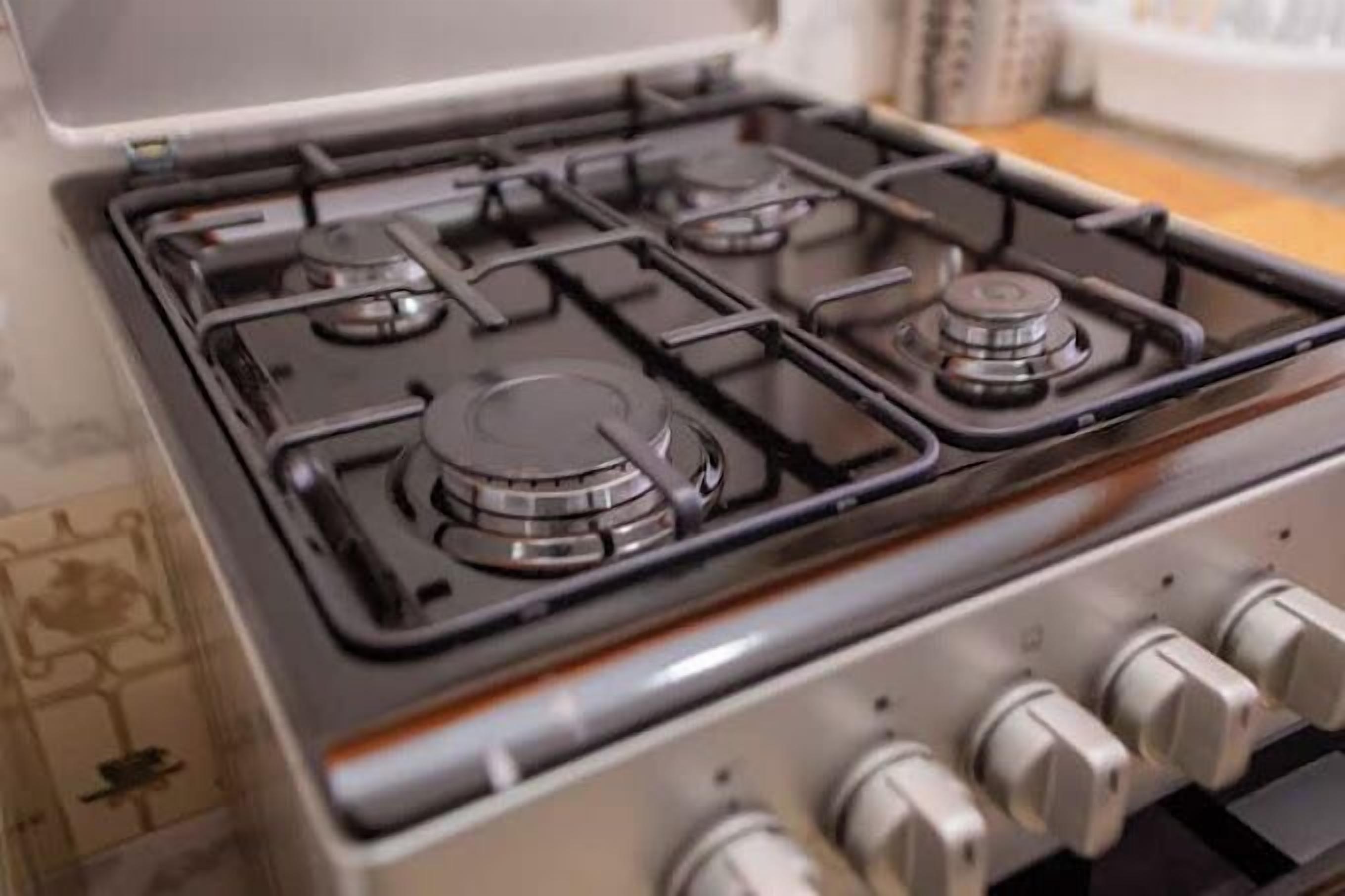 A gas stove with four burners and a control panel with knobs.
