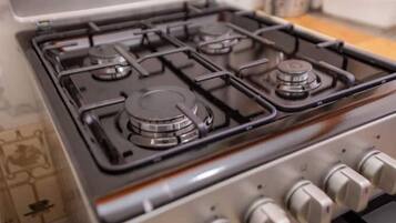 A gas stove with four burners and a control panel with knobs.