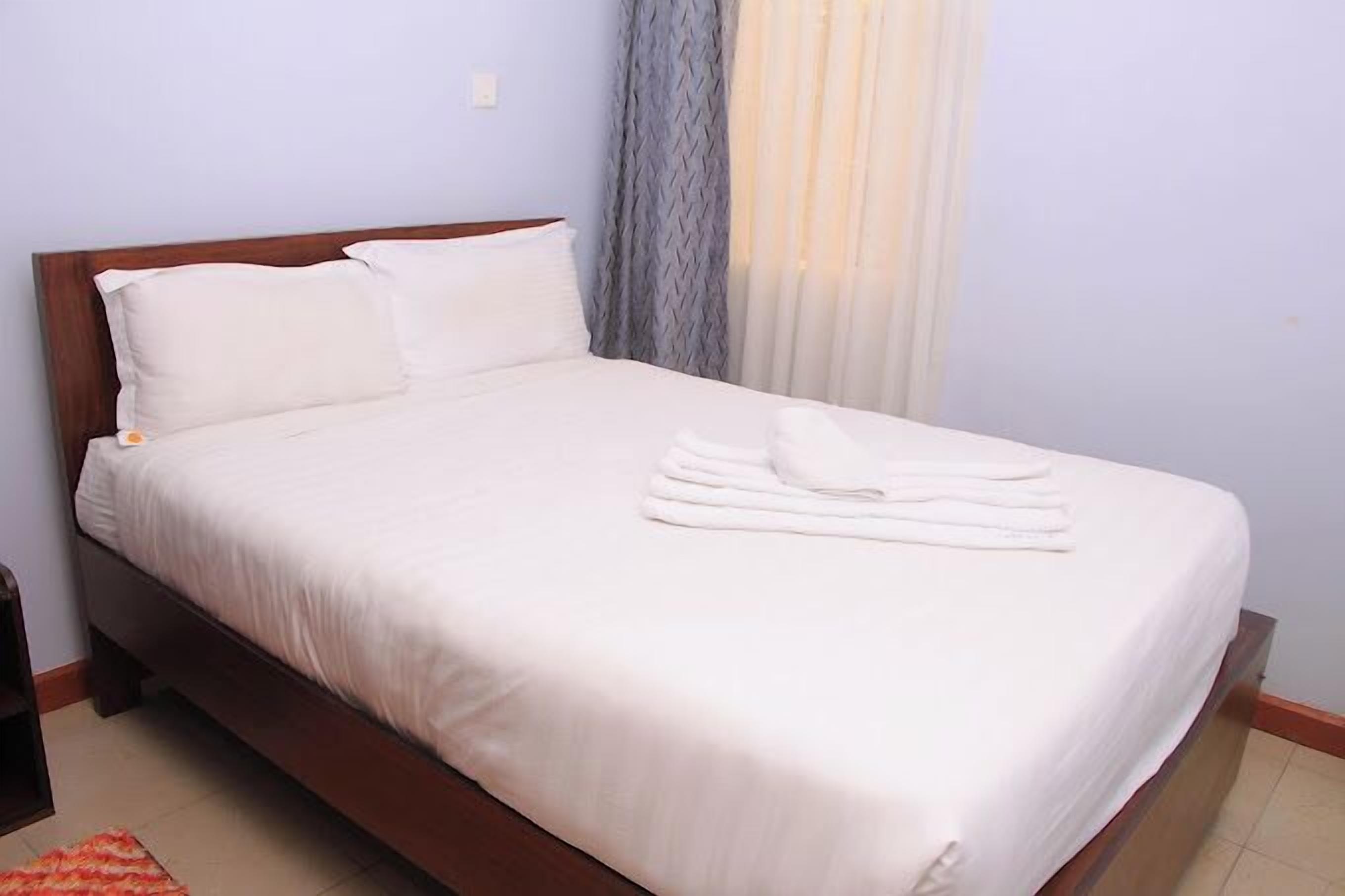A neatly made bed with white linens and a folded towel on the footboard.