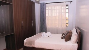 Ein Schlafzimmer mit Bett, Holzschrank und einem fenster mit Vorhängen.