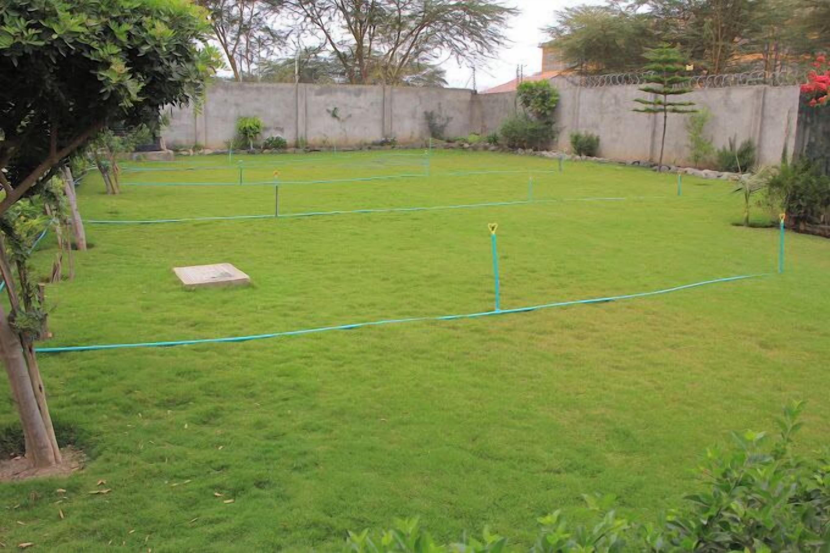 A well-maintained grassy area with a stone bench and a hose reel.