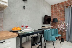 Un comedor moderno con pared de ladrillo, televisor de pantalla plana, una silla color turquesa y una planta en maceta.