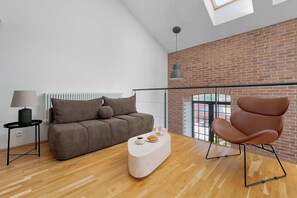 Een moderne woonkamer met een bank, een salontafel, een stoel, een lamp en uitzicht door een groot raam.