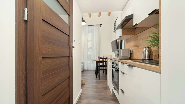 Een moderne keuken met witte kasten, een houten aanrechtblad en een magnetron.