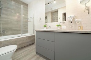 A modern bathroom with a glass-enclosed shower, a vanity with a sink, and a toilet.