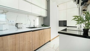 A modern kitchen with white cabinets, a marble backsplash, and a black countertop.