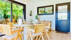 A dining area with a round table, wooden chairs, and a view of greenery outside. - Lili - Pool & View of Lake Carcès (Carcès)
