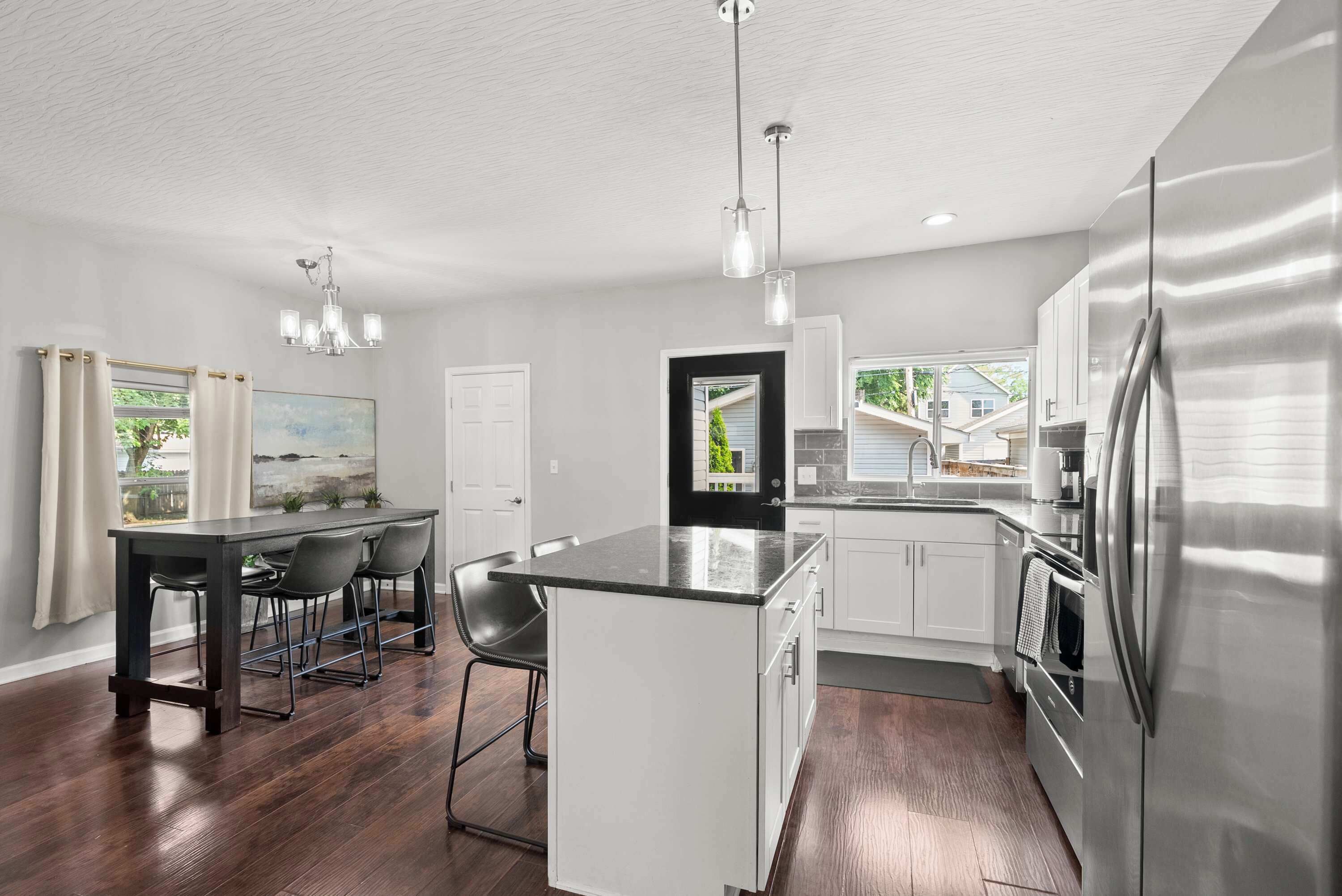 A modern kitchen with a central island, stainless steel appliances, and a dining area with a table and chairs.