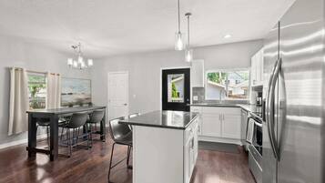 A modern kitchen with a central island, stainless steel appliances, and a dining area with a table and chairs.
