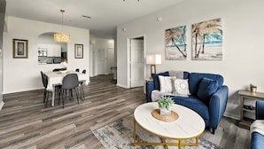 A spacious living area with a blue sofa, a dining table, and a kitchen in the background. - Epic Windsor Palms Resort Retreat (Kissimmee)