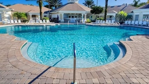 A pool area with lounge chairs, palm trees, and a building with a tiled roof. - Epic Windsor Palms Resort Retreat (Kissimmee)